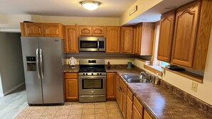 A kitchen with wooden cabinets, stainless steel appliances, and a granite countertop. - ​​2BR w/ Fireplace | Backyard Seating + Firepit (Wellsboro)