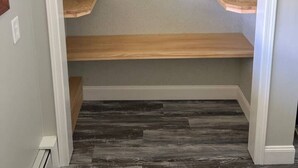 Un dressing avec trois étagères en bois et un plancher en bois foncé.