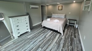 A bedroom with a skylight, a bed with a white comforter, a dresser, and a small bedside table. - Sunny 1BR w/ Game Room + Firepit | 10 min to Town (Wellsboro)
