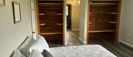 A bedroom with a large bed, wooden closet doors, and a hallway leading to another room.