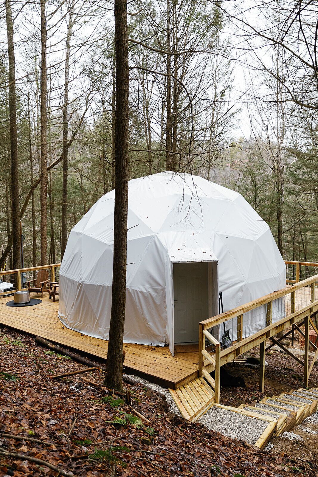 Une tente en forme de dôme dotée d’une terrasse en bois et d’un petit espace porche.