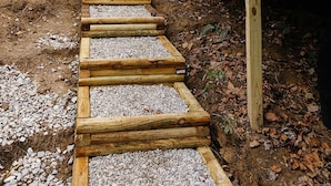 A wooden staircase leading to a covered area with a metal railing, surrounded by a forested area. - "The Perch" RRG - Modern Elevated Stay w/ Hot Tub (Campton)