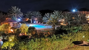 A nighttime view of a pool area with palm trees and illuminated lights. - Oasis Tilogui (Zagora)