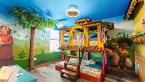 Ein Kinderzimmer mit Etagenbett, Wandmalerei und Schreibtisch mit Stuhl.