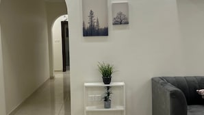 A modern living room with a grey sofa, a white console table with plants, and two framed pictures on the wall.