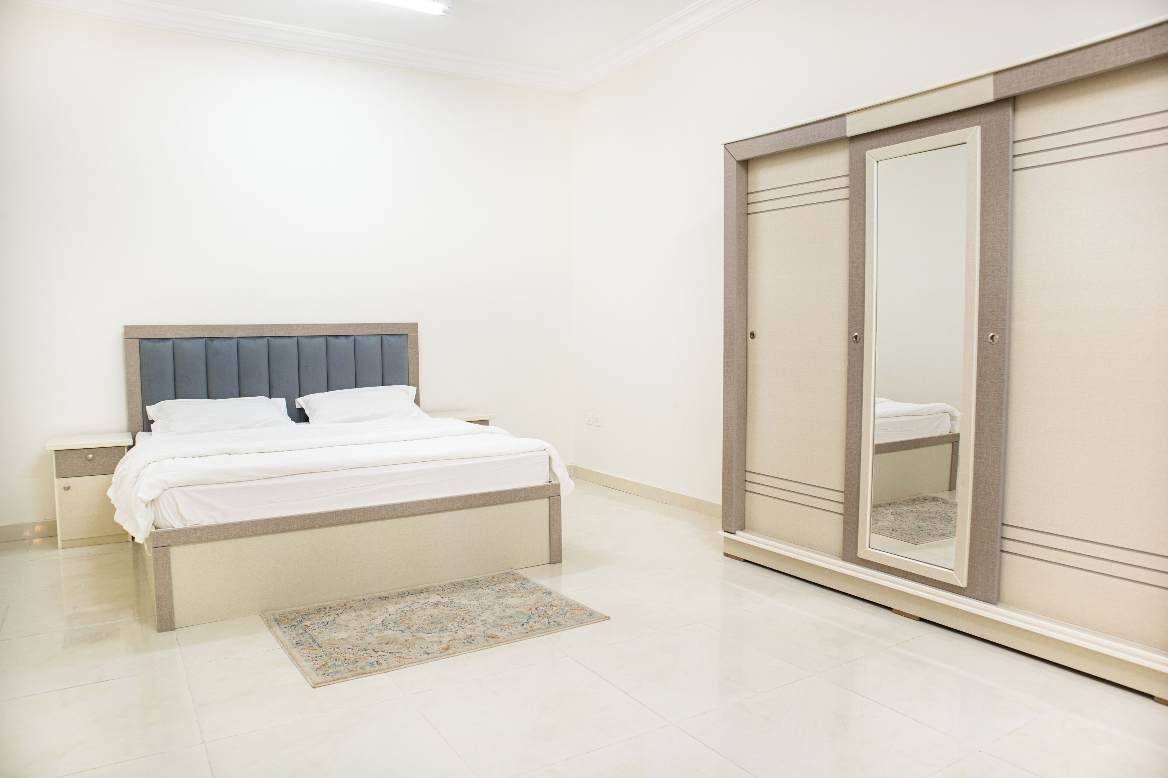 A bedroom with a bed, nightstands, a wardrobe, and a rug.
