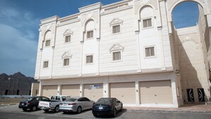 A multi-story building with a large arched entrance, several windows, and closed garage doors.