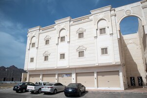 A multi-story building with a large arched entrance, several windows, and closed garage doors.
