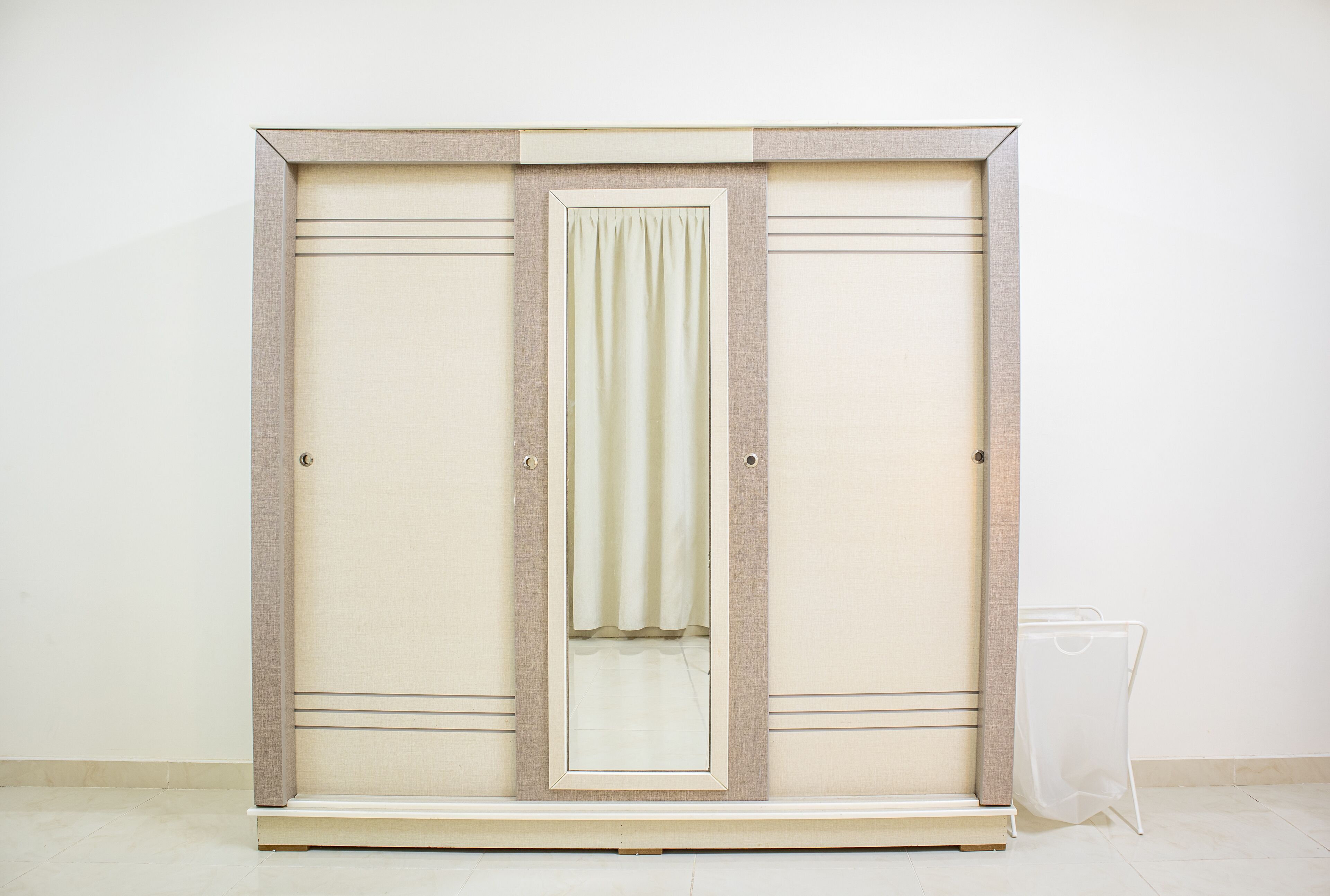 Ein Schrank mit Spiegel und Vorhang.