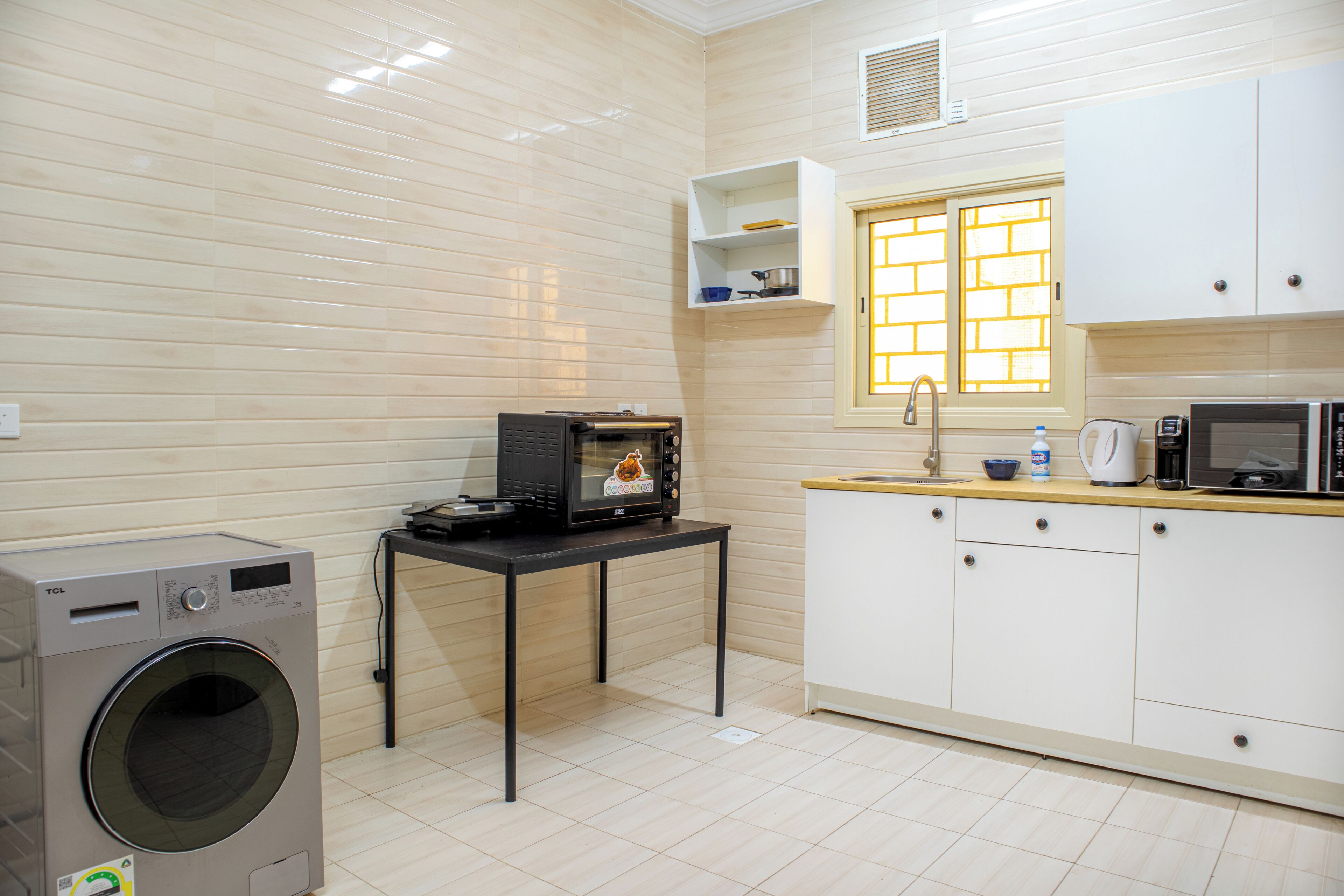 A compact kitchen with a washing machine, a microwave, and a small table.