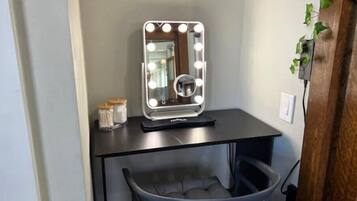 A vanity with a mirror, lights, and a chair.