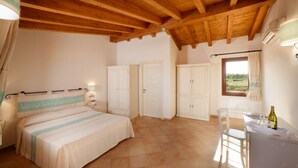 A bedroom with a bed, wardrobe, and a window with curtains. - Residence with pool in Vignola Mare  (Aglientu)