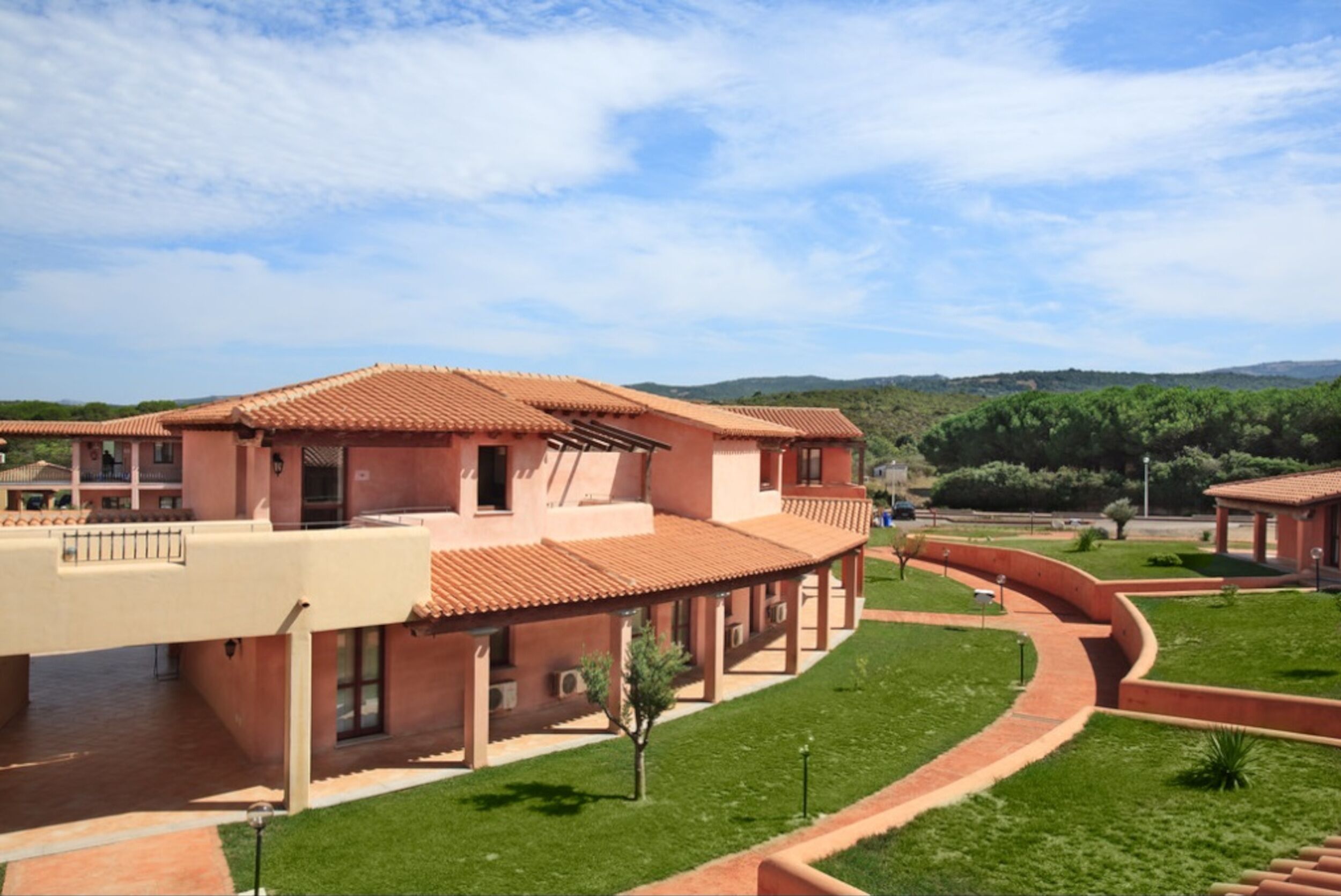 A large building with a terracotta roof, multiple balconies, and a well-maintained lawn.
