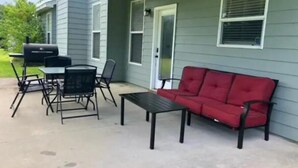 Un patio cubierto con un sofá rojo, una mesa y sillas.