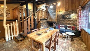 Un intérieur rustique avec une table à manger en bois, des chaises, un canapé et une cheminée.