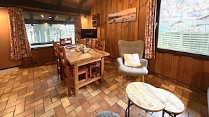 Un intérieur en bois comprenant une table à manger, des chaises, un canapé et une fenêtre donnant sur un paysage agréable.