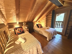 A wooden cabin with two beds, a fireplace, and a balcony. - L'OURS NOIR Chalet en rondins (La Bresse)