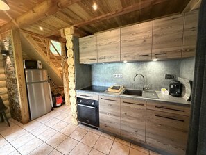 Una cocina compacta con armarios de madera, horno empotrado, microondas y lavamanos.