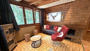 A cozy cabin interior with a fireplace, wooden walls, a sofa, and a dining table. - LE RENNE  Chalet en bois au calme avec SPA Jacuzzi (La Bresse)