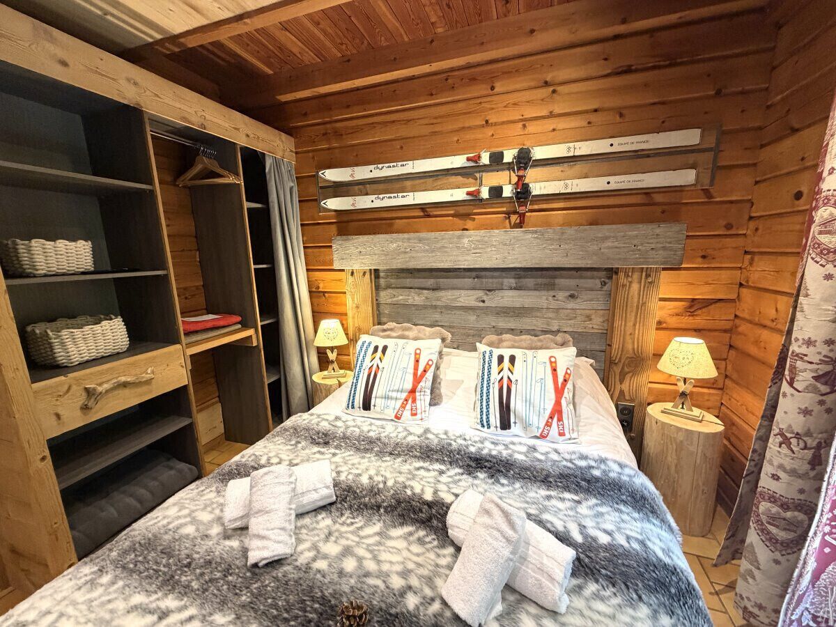 Une chambre de style cabane en bois, avec un lit, une armoire et un porte-skis.