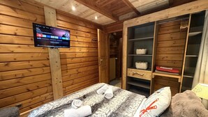 A wooden room with a bed, a TV, and a wooden wardrobe.