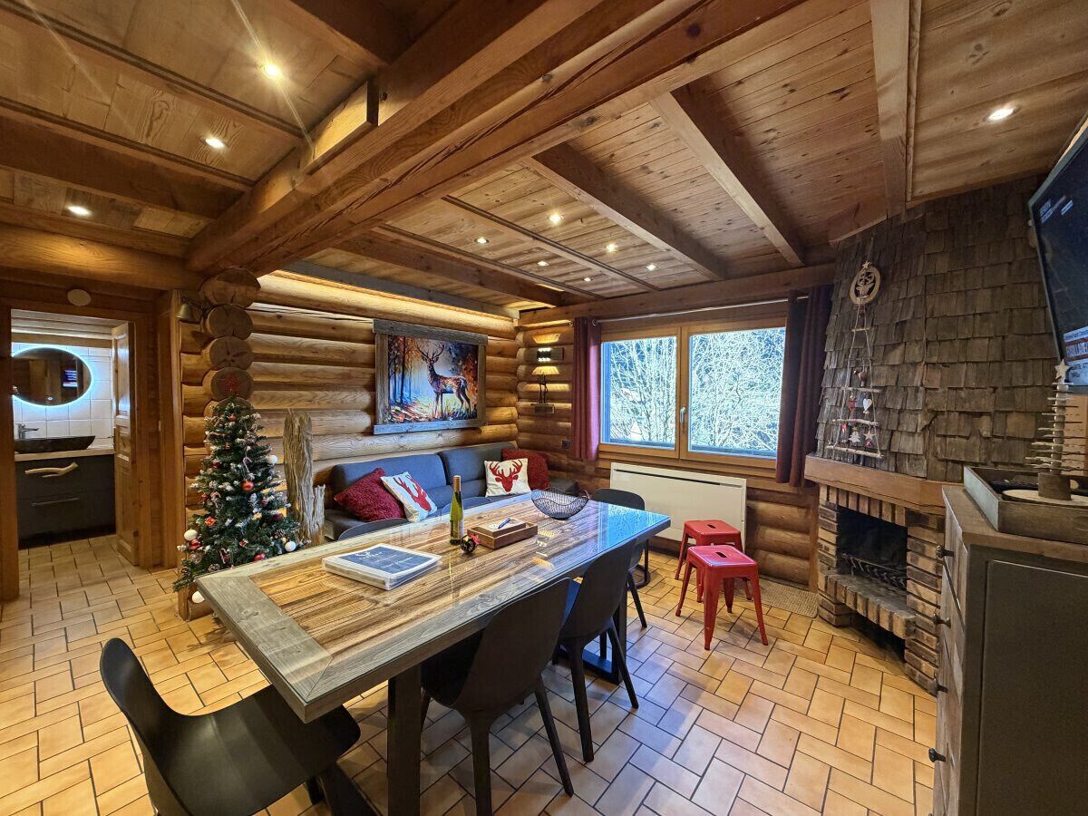 L’intérieur d’une cabane en rondins, avec un coin repas, une cheminée et un sapin de Noël.