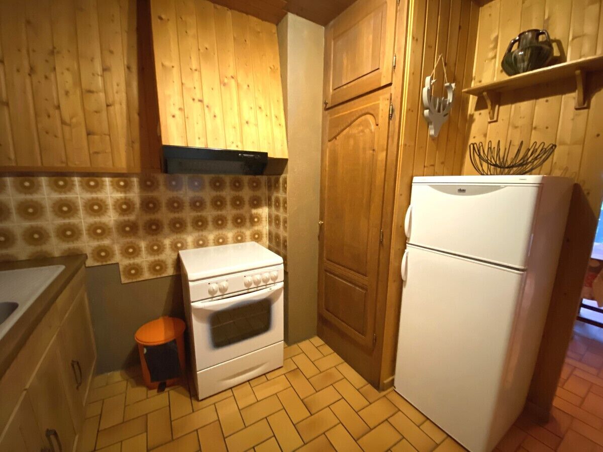 Una cocina funcional con armarios de madera, estufa blanca y refrigerador blanco.