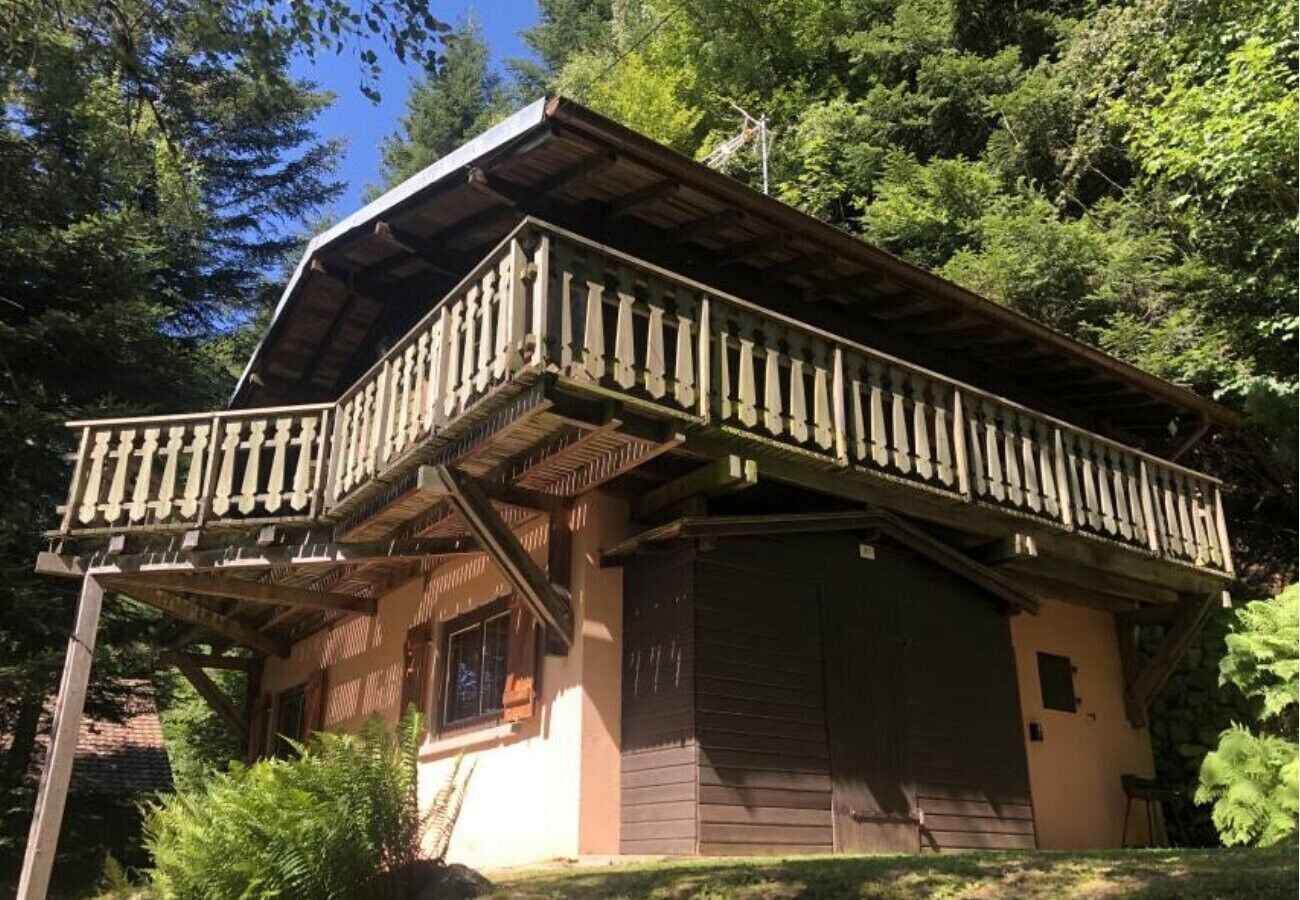 Une cabane en bois dotée d’un balcon, entourée d’arbres.