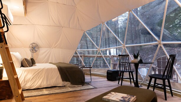 A spacious tent with a bed, a fan, and a table with chairs. - “Climber's Den” Rare Cliffside Stay w/ HotTub RRG (Campton)