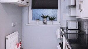 A compact kitchen with white cabinets, a black countertop, a window with a view, and a built-in oven. - Stunning 2-bed Apartment in London (London)