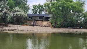 Una casa con una piscina pequeña, rodeada de árboles y un cielo despejado.