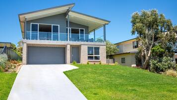 A modern two-story house with a large garage, a covered balcony, and a well-maintained lawn.