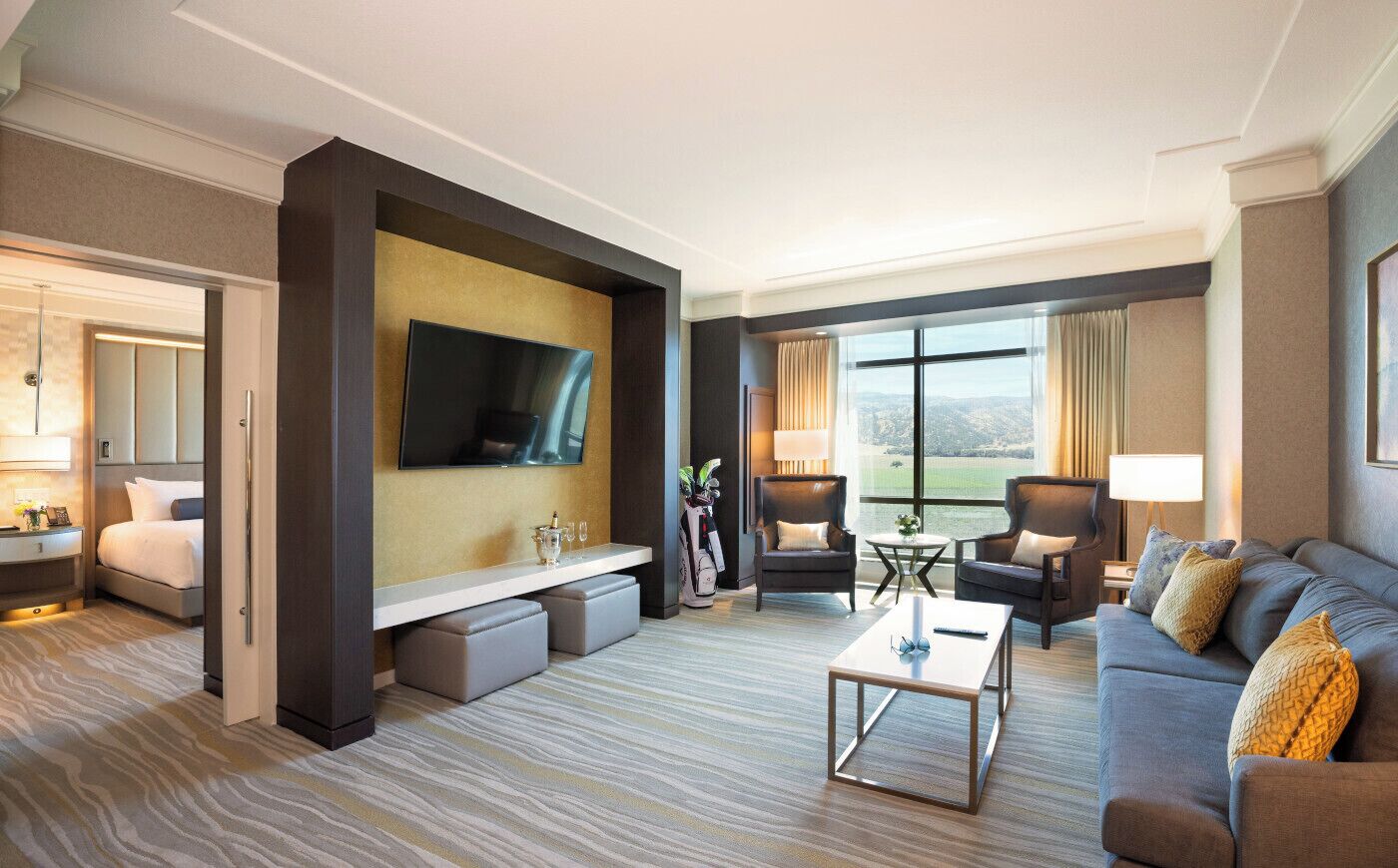 A hotel room with a bed, a TV, a sofa, a coffee table, and a view of the outdoors.