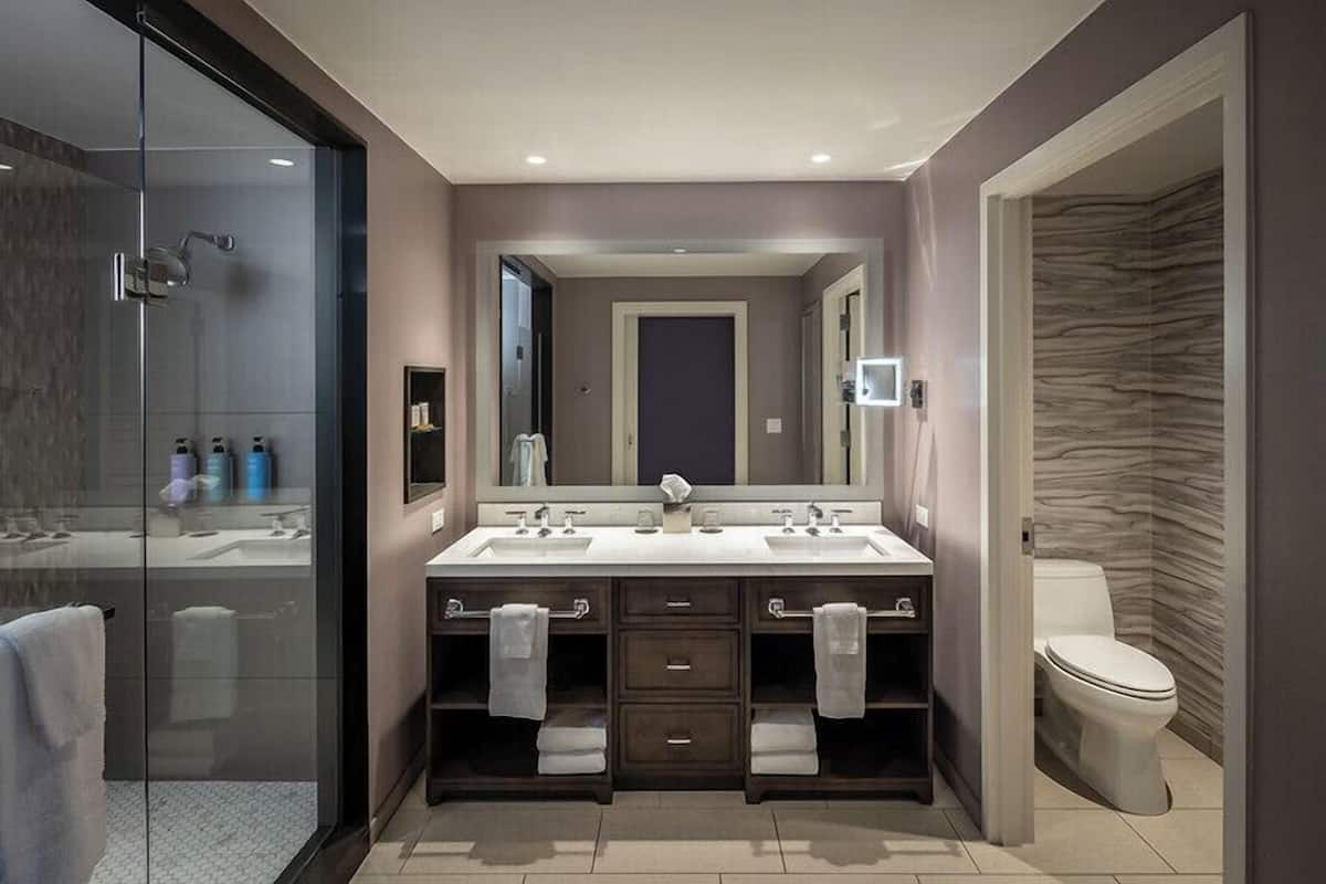 Un baño moderno con cabina de ducha de vidrio, tocador doble y un inodoro.