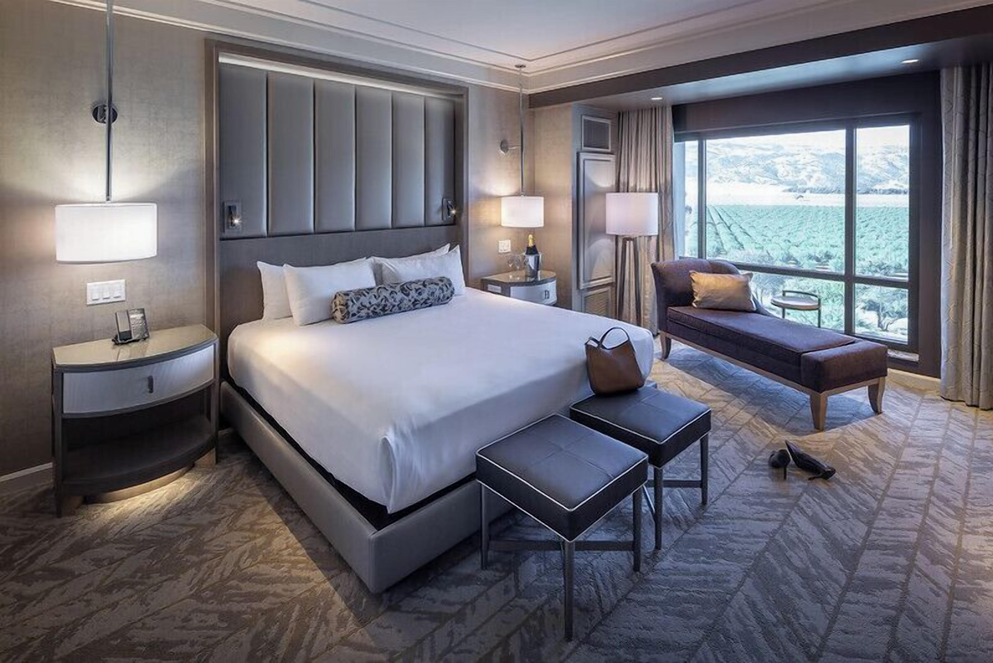 Een hotelkamer met een groot bed, nachtkastjes, een bank en uitzicht op de omgeving.