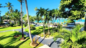 Een resort met een verzorgd gazon, palmbomen en een helder uitzicht op de oceaan.