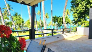 Een balkon met uitzicht op palmbomen en een strand.