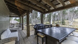 A covered outdoor area with a wooden table and chairs, a grill, and a view of trees. - Modern spacious 5 bedroom, 3.5 bath, paved roads, hot tub, wifi, pool access (Lead)