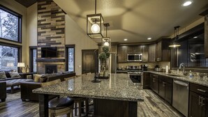 A modern kitchen with granite countertops, stainless steel appliances, and a large island with bar stools. - Modern spacious 5 bedroom, 3.5 bath, paved roads, hot tub, wifi, pool access (Lead)
