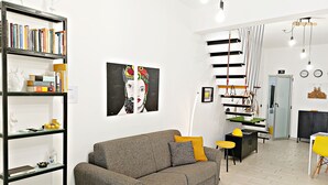 A modern living room with a grey sofa, a bookshelf, and a painting on the wall. - Aurelio's Artpartment - "Unconventional House" (Siracusa)