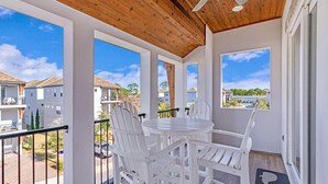 Un balcon avec des chaises blanches et une table, donnant sur un quartier résidentiel.