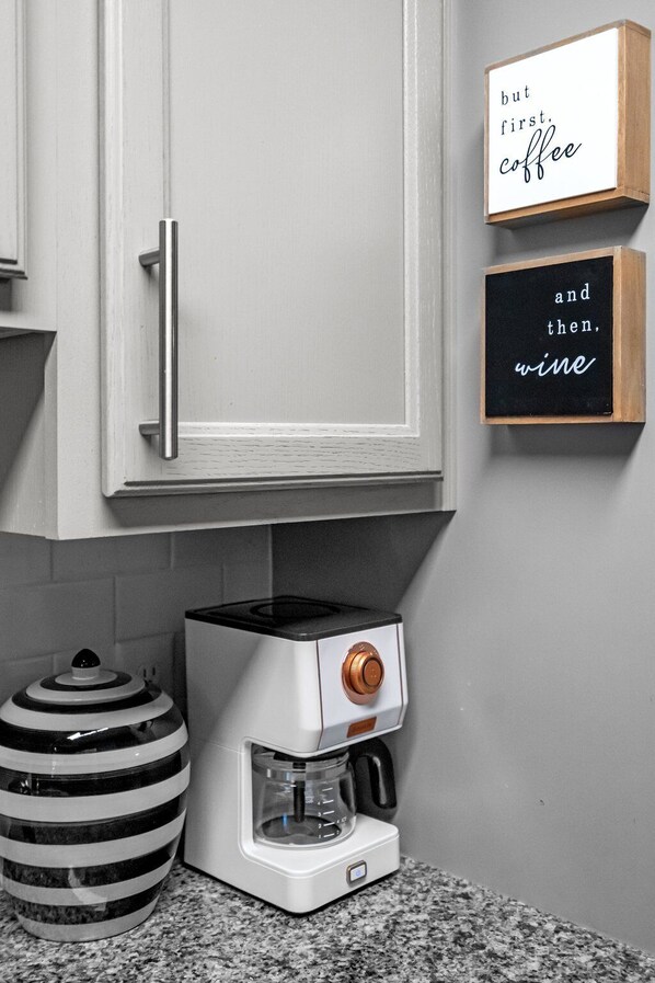 A kitchen with a coffee maker, a striped vase, and two signs on the wall. - The Jewel Box- NC State/ Walkable (Raleigh)