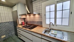 A modern kitchen with a gas stove, stainless steel sink, and a window with frosted glass panels. - Spectacular Five Senses Mallorca Apartment (Barcelona)