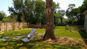 A backyard with a barbecue grill, two lawn chairs, a tree, and a stone pathway. - Ty Boca - Maison pour 6 avec jardin (Dinéault)
