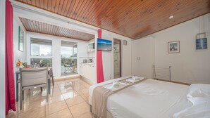 A hotel room with a bed, a desk, a chair, a bathroom, and a view of the outside. - Studio 204 - Vanille - Proche plage (Les Trois-Îlets)