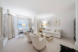 Ein modernes Wohnzimmer mit einem Glastisch, einem weißen Sofa und einem Essbereich mit einem Glastisch.