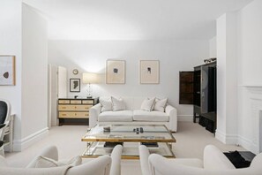 Ein modernes Wohnzimmer mit einem weißen Sofa, einem Glastisch und einem Kamin.