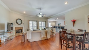 A spacious living room with a fireplace, a dining area with wooden chairs, and a ceiling fan. - Spacious Zachary Home: 12 Mi to Baton Rouge! (Zachary)