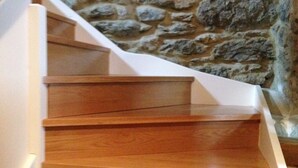 Een houten trap met witte leuningen die naar een stenen muur leidt.