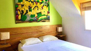 Une chambre d’hôtel avec un lit, deux tables de chevet, une tête de lit en bois et un tableau abstrait aux couleurs vives accroché au mur.